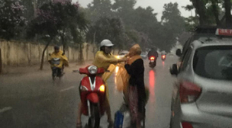 Cô gái trẻ dừng xe mặc áo mưa cho cụ già trong cơn dông trắng xóa